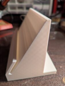 Side view of the printed monitor stand, clearly showing the slot to hold the monitor. The stand is white.